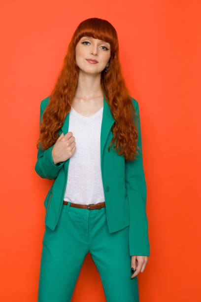 istock Confident young red haired woman is posing in green suit. 1362876409