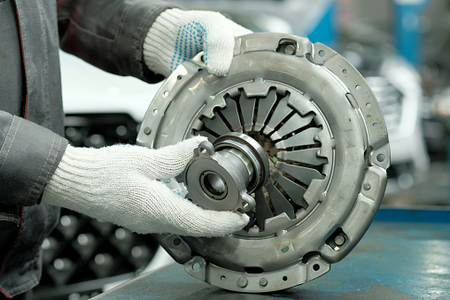 An auto mechanic checks the technical condition of the drive disc, the driven disc and the exhaust bearing. Repair and maintenance in a car service.
