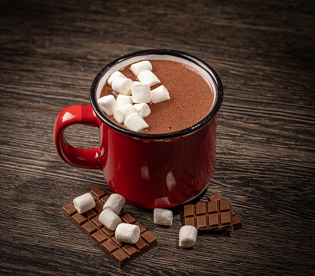 Hot cocoa with marshmallow and chocolate in a red ceramic mug