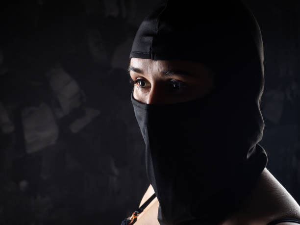 Portrait of a girl in a black balaclava and a black bra. stock photo