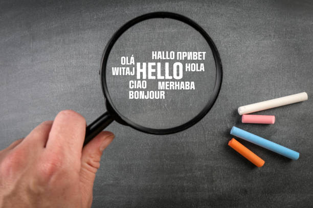 istock Hello. Text in different world languages. Magnifying glass on a dark blackboard background 1362878990