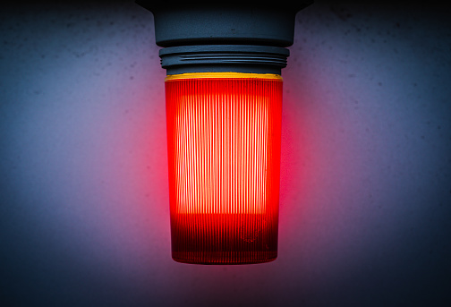 Close-up of an industrial red light outside of a building with vignette.