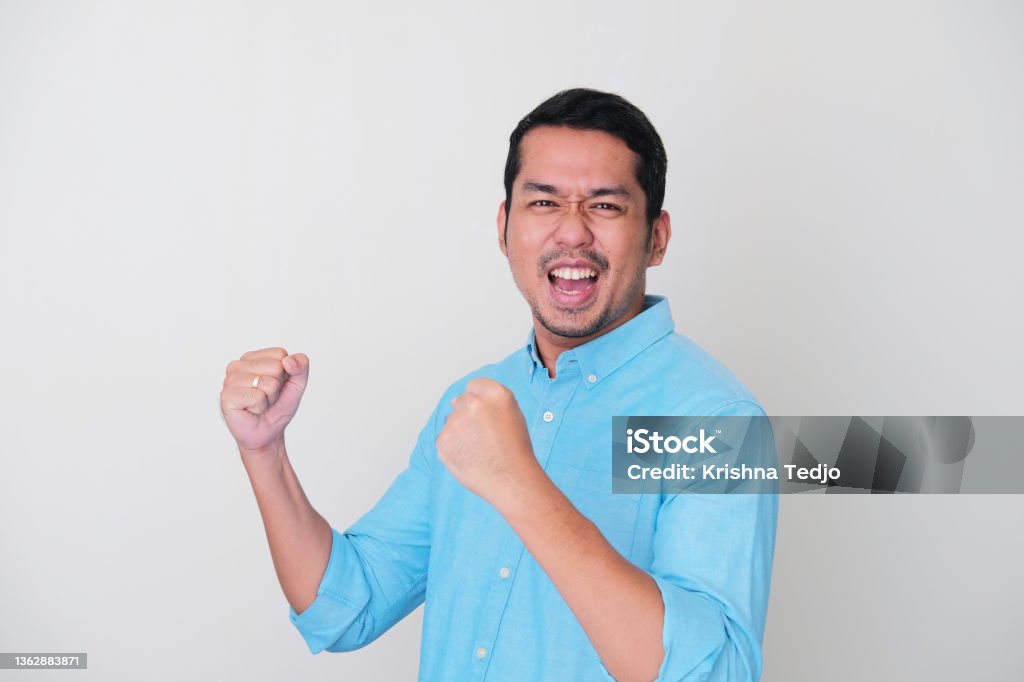 Adult Asian man showing success gesture with his both hand clenched Men Stock Photo