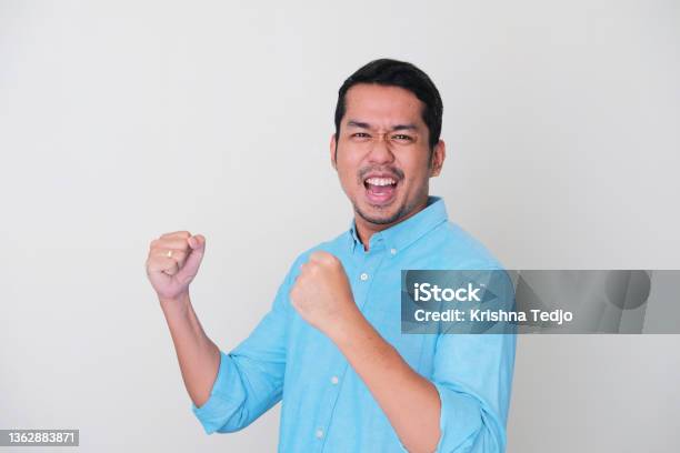 Adult Asian Man Showing Success Gesture With His Both Hand Clenched Stock Photo - Download Image Now