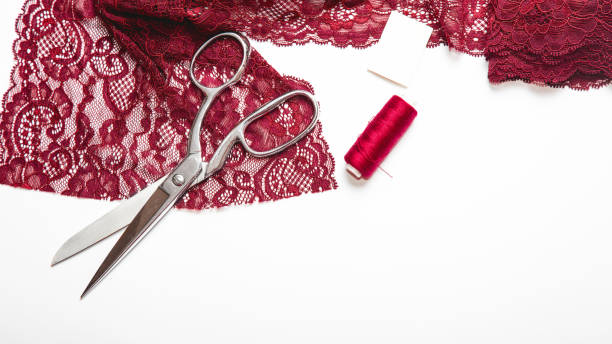istock Red, burgundy lace fabric scissors, thread spools. Tailor designer workplace concept. 1362885135