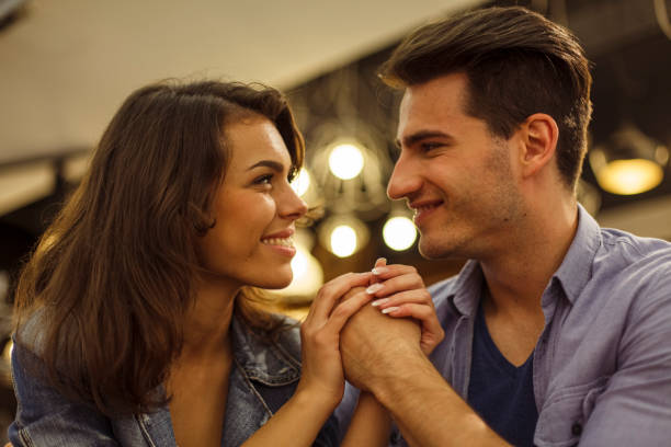 istock Couple holding hands, smiling at each other, falling in love 1362890058
