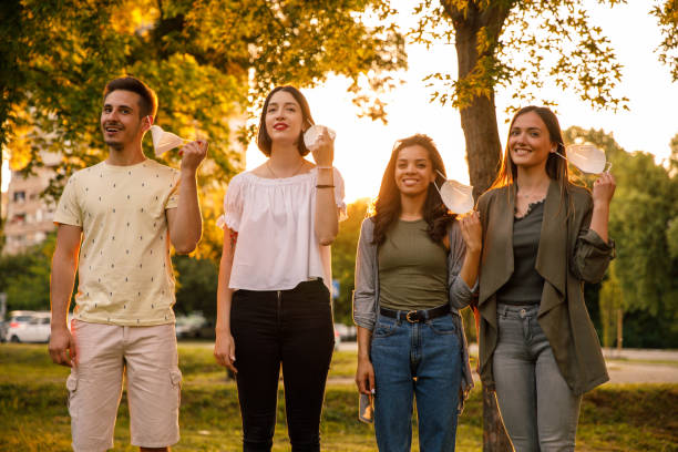 istock Four young people smiling at camera while removing N-95 face masks 1362890540
