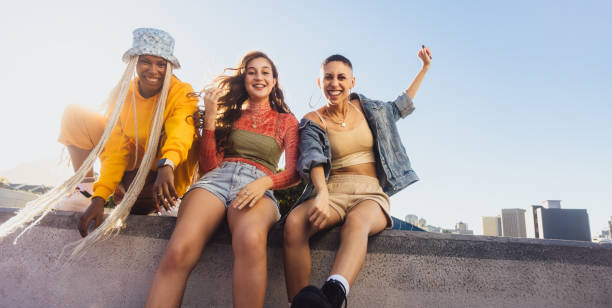 istock Three female friends smiling while sitting on a wall 1362891642