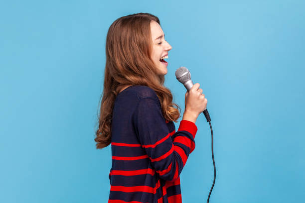 Woman standing with microphone, singing her favorite songs in karaoke, talented singer performing. stock photo