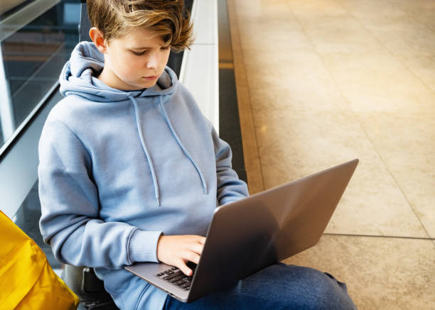 istock Child boy with a laptop studying or entataining at public space 1362893360