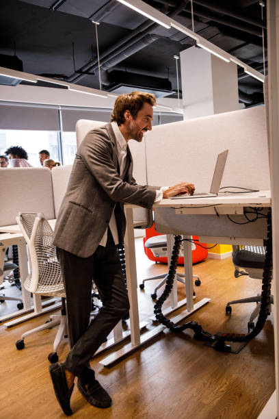istock Businessman working at standing desk and tying data on laptop 1362893650
