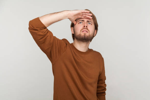 istock Man with beard wearing sweatshirt, standing with hand on forehead and looking for something. 1362893790