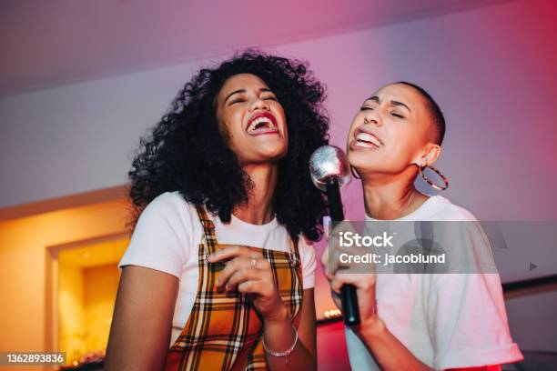 Best Friends Singing Into A Microphone On Karaoke Night Stock Photo - Download Image Now