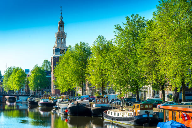 A peaceful panoramic morning view of Montelbaans Tower and the city  reflecting in the canals of Amsterdam, Netherlands. Landscape, vivid urban scene.