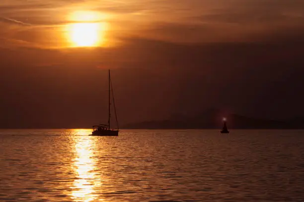 Yacht passing a navigation mark inbound to Uvala Luka, Cavtat, Croatia, at sunset