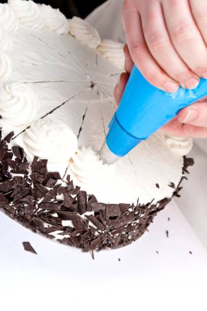 istock Pastry chef decorating a gateau with cream swirls 1362901488