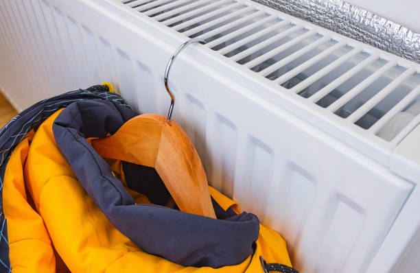 Drying a children's winter jacket on a heating radiator. stock photo