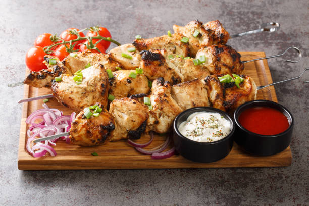 Grilled chicken shish kebab or shashlik on skewers closeup on board close-up. Horizontal Grilled chicken shish kebab or shashlik on skewers closeup on wooden board close-up. Horizontal chicken skewer stock pictures, royalty-free photos & images