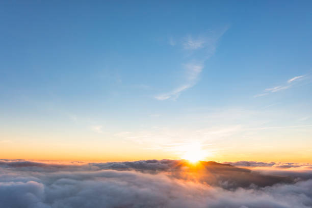 istock Sun shining above layer of white fluffy clouds at sunset 1362902631