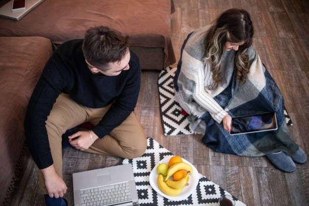 istock A young couple is sitting on the floor in their home, using a laptop 1362902941
