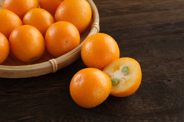 frutas kumquat sobre mesa de madera - kumquat fotografías e imágenes de stock