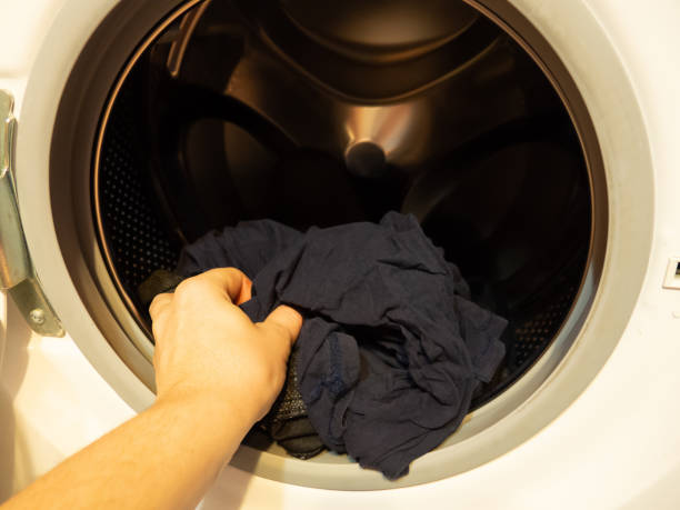 istock man puts clothes in the washing machine, close-up 1362904457