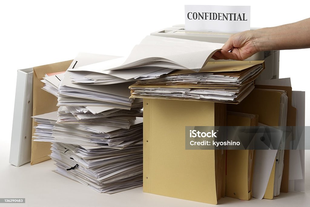 Isolated shot of paper shredder with documents on white background The hand which has confidential documents on white background. Wastepaper Basket Stock Photo