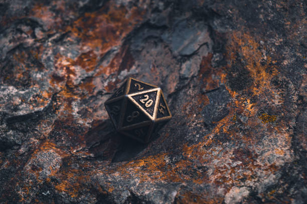 Metal D20 on a rocky surface with orange lichen stock photo