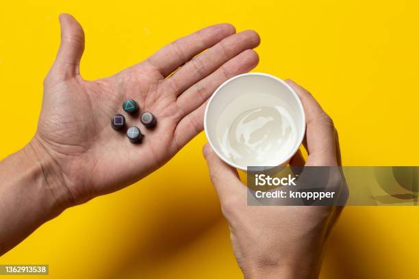 Playstation Buttons On The Palm And A Glass Of Water Stock Photo - Download Image Now