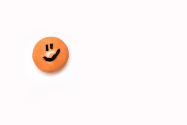 single orange smiling face on round candy on white background