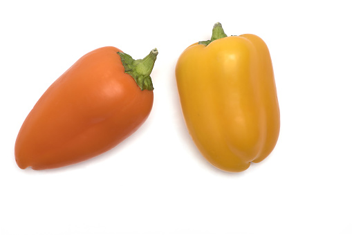 two colored snack bell pepper pod in orange and yellow on white background paprika