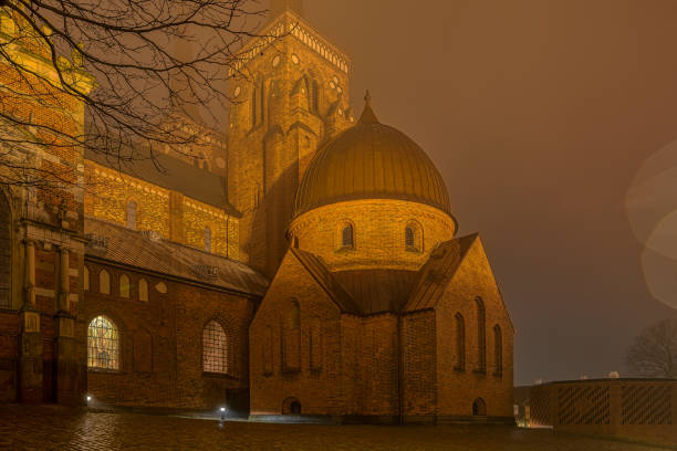 la catedral iluminada de roskilde una noche brumosa - roskilde fotografías e imágenes de stock