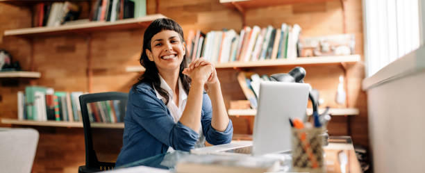 confident young businesswoman smiling in her home office - business women computer cheerful imagens e fotografias de stock