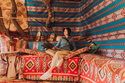 Young smiling woman resting inside the colorful tent during hiking in old Petra town in the Middle East