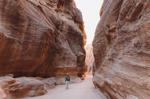 Young woman explorer hiking in the beautiful pink canyon in the old town of Petra in the Middle East