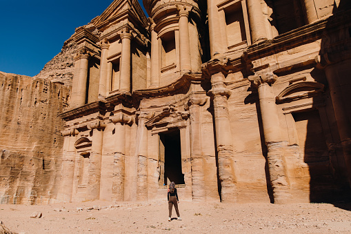Young woman explorer in headscarf walking at the old town of Petra during sunny day in the Middle East
