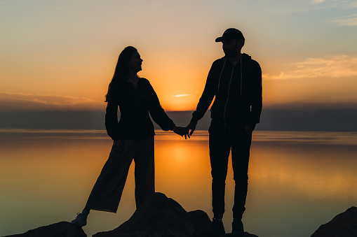 Couple sitting together on grass in seaside park at sunset time