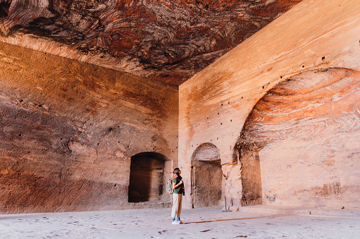 Young woman explorer  walking at the old town of Petra looking for the old painting on the walls in the Middle East