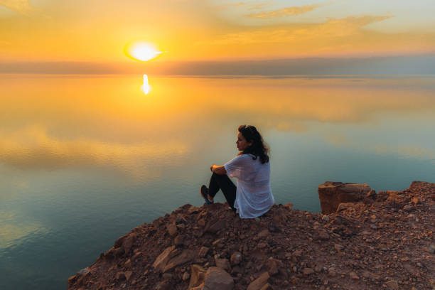 Silhouette of woman contemplating the scenic sunset above the Dead Sea in Jordan stock photo