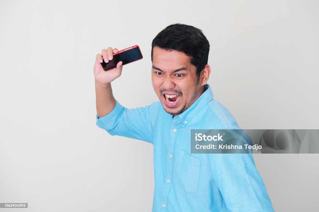 Adult Asian man showing rage expression and want to slam his mobile phone Throwing Stock Photo