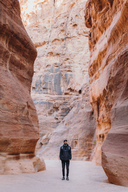 viaggiatore maschio che esplora l'antico mondo di petra in giordania camminando all'interno del canyon - ancient wonder foto e immagini stock