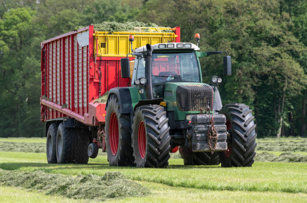 istock Picking up dried grass for silage with a green tractor and red loader wagon 1362925500