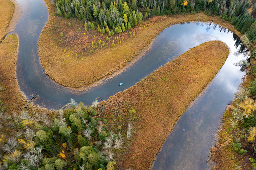 Aerial view of a solo kayaker paddling along a curve of a meandering river in Northern Minnesota