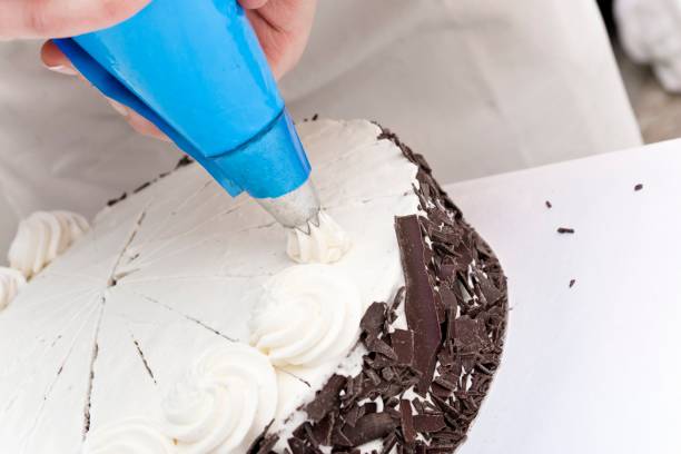 istock Pastry chef decorating a gateau artfully with cream swirls 1362927987