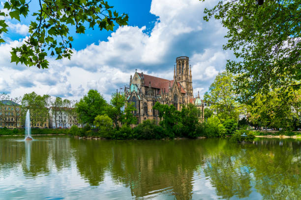 Germany, Stuttgart city downtown feuersee urban park st john church reflecting in lake water between green trees stock photo