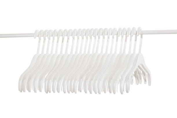 White plastic hangers for clothes hanging on rod from clothing rack. Isolated on white background.. White plastic hangers for clothes hanging on rod from clothing rack. Isolated on white background. clothes hanger rod stock pictures, royalty-free photos & images