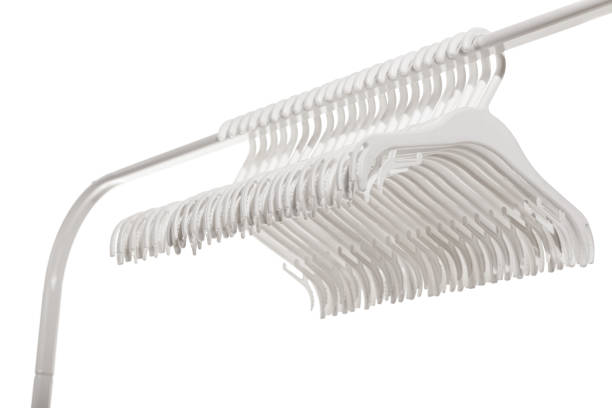 White plastic hangers for clothes hanging on rod from clothing rack. Isolated on white background.. White plastic hangers for clothes hanging on rod from clothing rack. Isolated on white background. clothes hanger rod stock pictures, royalty-free photos & images
