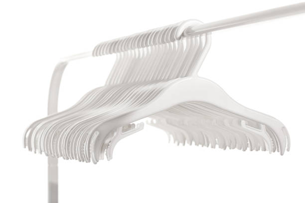 White plastic hangers for clothes hanging on rod from clothing rack. Isolated on white background.. White plastic hangers for clothes hanging on rod from clothing rack. Isolated on white background. clothes hanger rod stock pictures, royalty-free photos & images