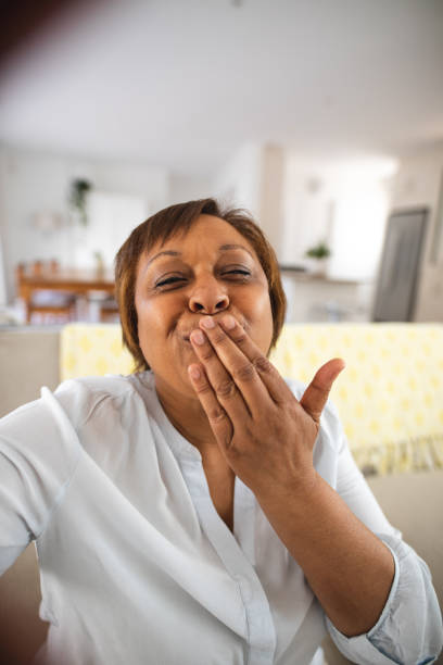 Happy african american senior woman blowing kiss during video call at home Happy african american senior woman blowing kiss during video call at home. lifestyle and communication. blowing a kiss stock pictures, royalty-free photos & images