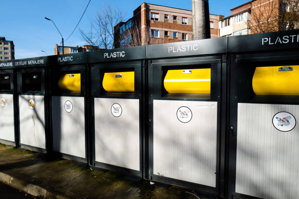 Color image depicting plastic recycling bins in a row on a city street.
